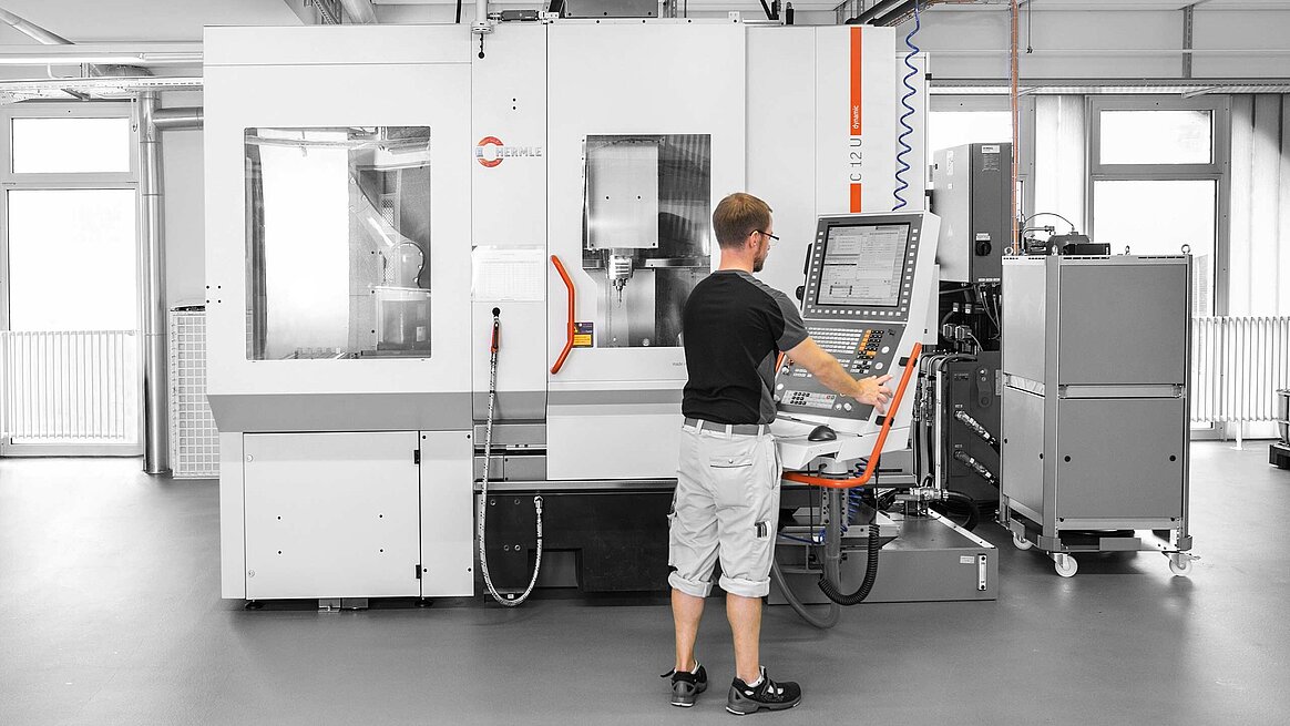 Das Bearbeitungszentrum C 12 U mit Werkzeug-Zusatzmagazin ZM 35 und links dem Robotersystem RS 05 von Hermle wird von Mitarbeiter bedient